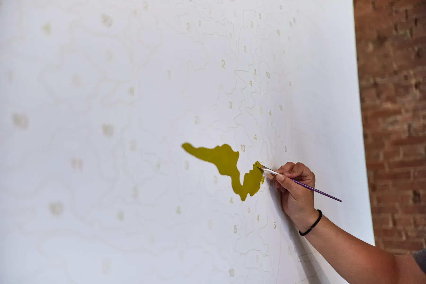 Guest painting a numbered section of the Ed Sheeran Subtract paint-by-number mural